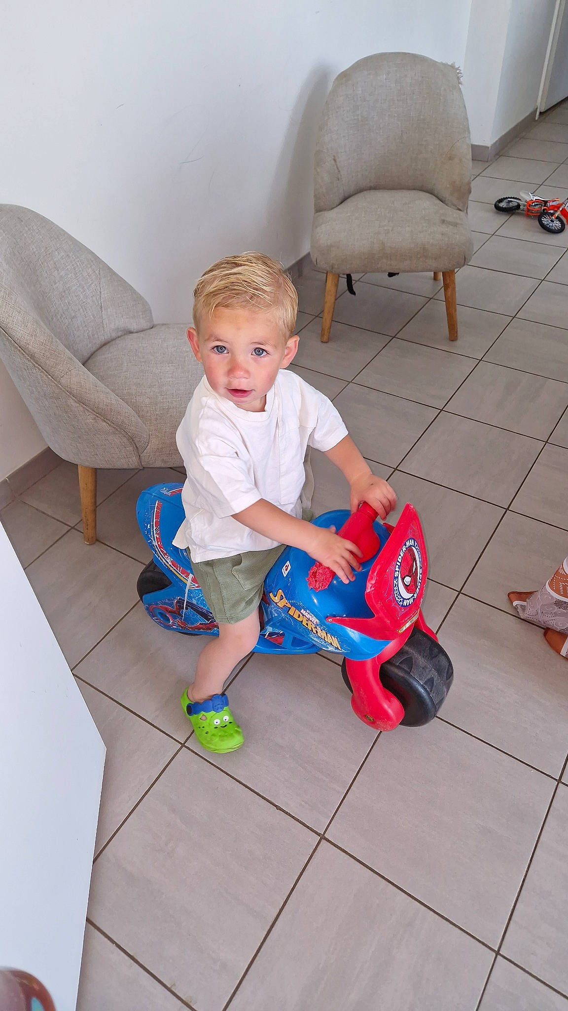 Mahonn participe au concours pour gagner de l'argent avec cette photo : baby_toddler_clothing, chair, child, comfort, couch, floor, flooring, fun, hardwood, human_leg, knee, lap, leisure, person, sitting, sock, toddler, toy, toy_vehicle, white