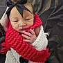 baby, newborn, infant, bow, headband, red_scarf, knitted_scarf, white_blanket, wrapped, hand, fingers, face, sleepy, cozy, portrait, closeup, button, dark_background, bracelet, knitwear