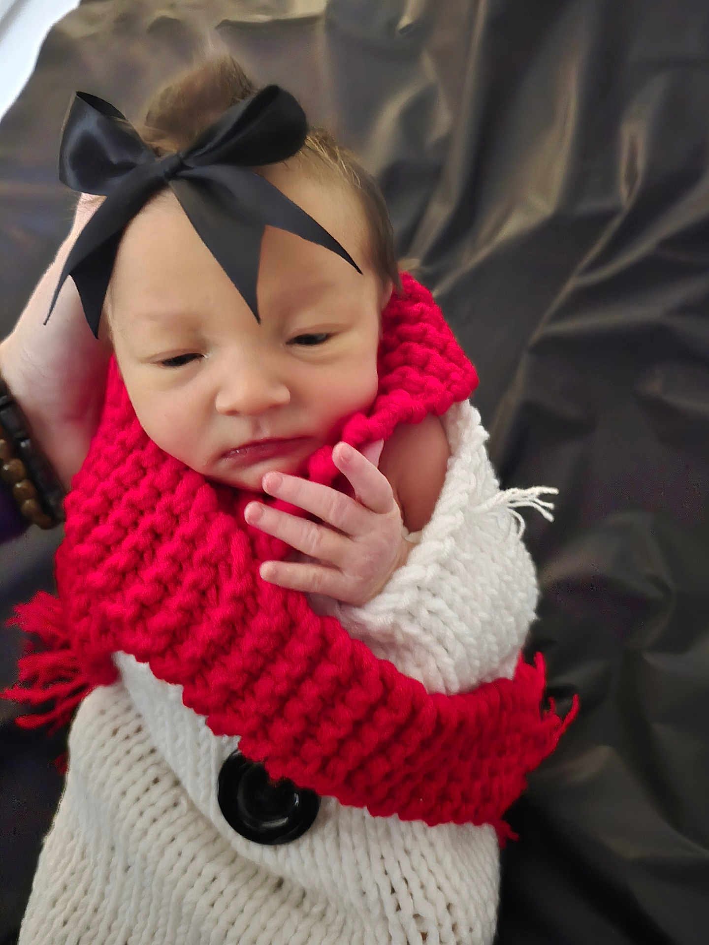 Bailynn Renea joined the competition — help win amazing prizes! baby, newborn, infant, bow, headband, red_scarf, knitted_scarf, white_blanket, wrapped, hand, fingers, face, sleepy, cozy, portrait, closeup, button, dark_background, bracelet, knitwear
