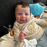 Peyton is registered to the contest to win money with this photo: baby, smile, infant, striped_clothing, elephant_patch, couch, blanket, fabric, hand, face, cute, happy, child, indoors, soft_toy, blue_blanket, person, portrait, cozy, texture