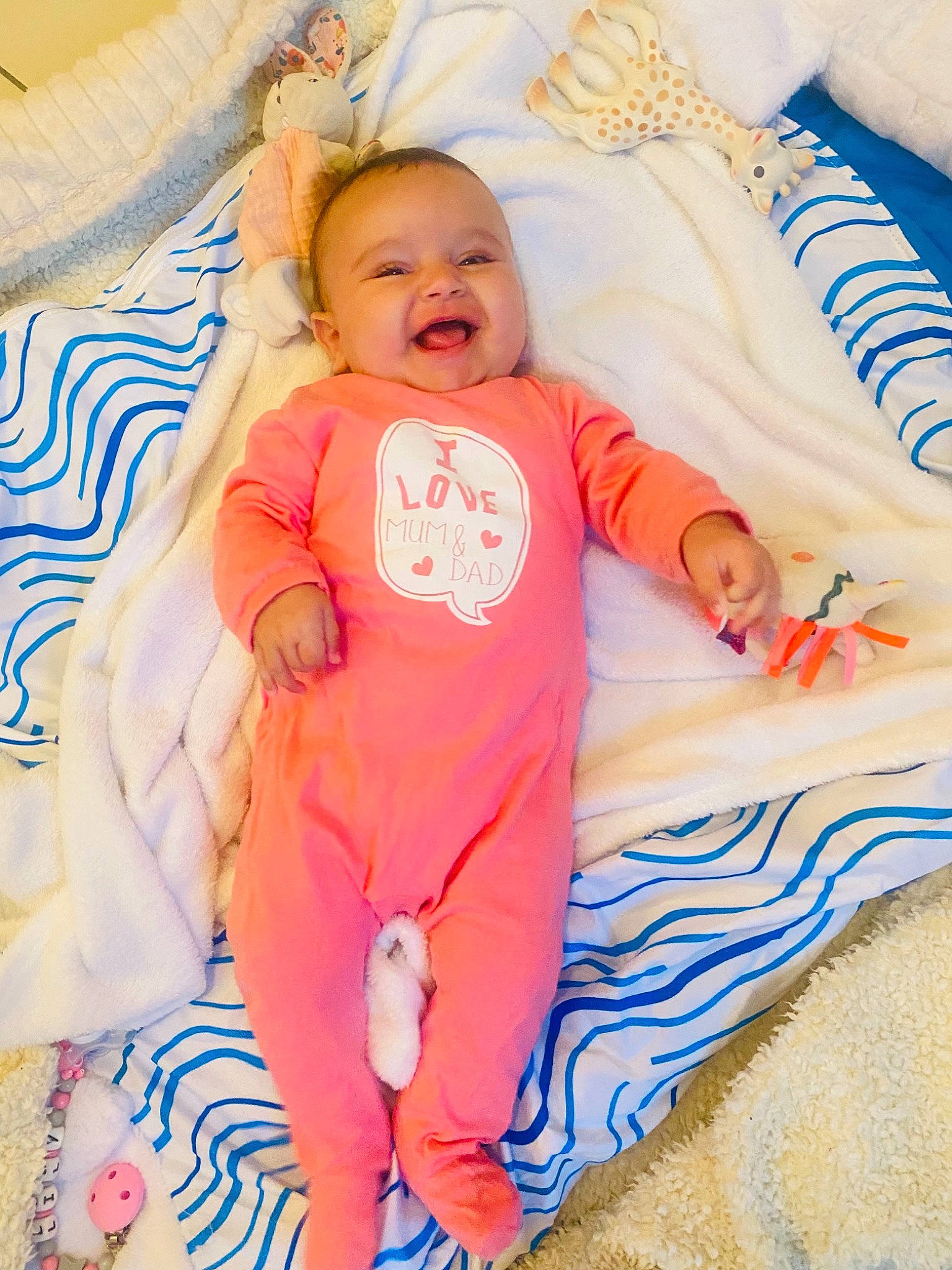 Lily participe au concours pour gagner de l'argent avec cette photo : baby, baby_products, baby_toddler_clothing, bedding, child, comfort, event, finger, fun, happy, linens, orange, pattern, person, pillow, skin, sleeve, smile, t_shirt, toddler