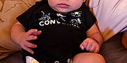 Joshua joined the competition — help win amazing prizes! baby, infant, diaper, black_shirt, bed, pillow, patterned_pillow, lying_down, curious, wide_eyes, chubby, hands, legs, indoor, person, cute, young_child, soft_lighting, skin, face