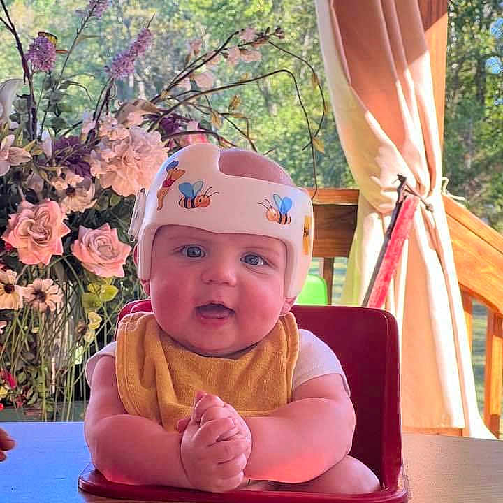 Beau is registered to the contest to win money with this photo: accessories, baby, chair, diningtable, face, flower, furniture, head, indoors, interiordesign, person, petal, photography, plant, portrait, pottedplant, rose, sitting, table, wood
