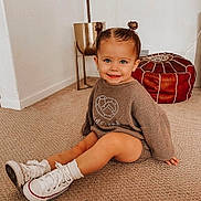 Baylee is registered to the contest to win money with this photo: carpet, casual, child, cute, earrings, floor, footwear, hair_buns, happy, home, indoor, person, plush_pouf, portrait, sitting, smile, sweater, toddler, white_sneakers, young_child