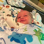 Zaidyn is registered to the contest to win money with this photo: baby, baseball, basketball, blanket, bottle, child, clothing, cute, dinosaur, face, football, indoors, infant, lying_down, newborn, portrait, smile, soft_surface, sports_pattern, towel