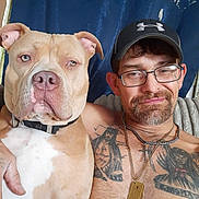 Cinnamon joined the competition — help win amazing prizes! man, dog, pet, portrait, indoor, tattoo, glasses, cap, necklace, shirtless, brown_dog, white_dog, closeup, face, smile, furniture, blue_curtain, companion, animal, friendship