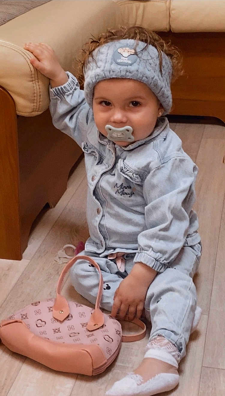 Livina a rejoint le concours — aidez-le/la à gagner de superbes lots ! child, toddler, pacifier, headband, denim_jacket, jeans, pink_purse, sitting, curly_hair, socks, indoor, wooden_floor, sofa, couch, hand, face, portrait, accessory, baby_clothes, smile