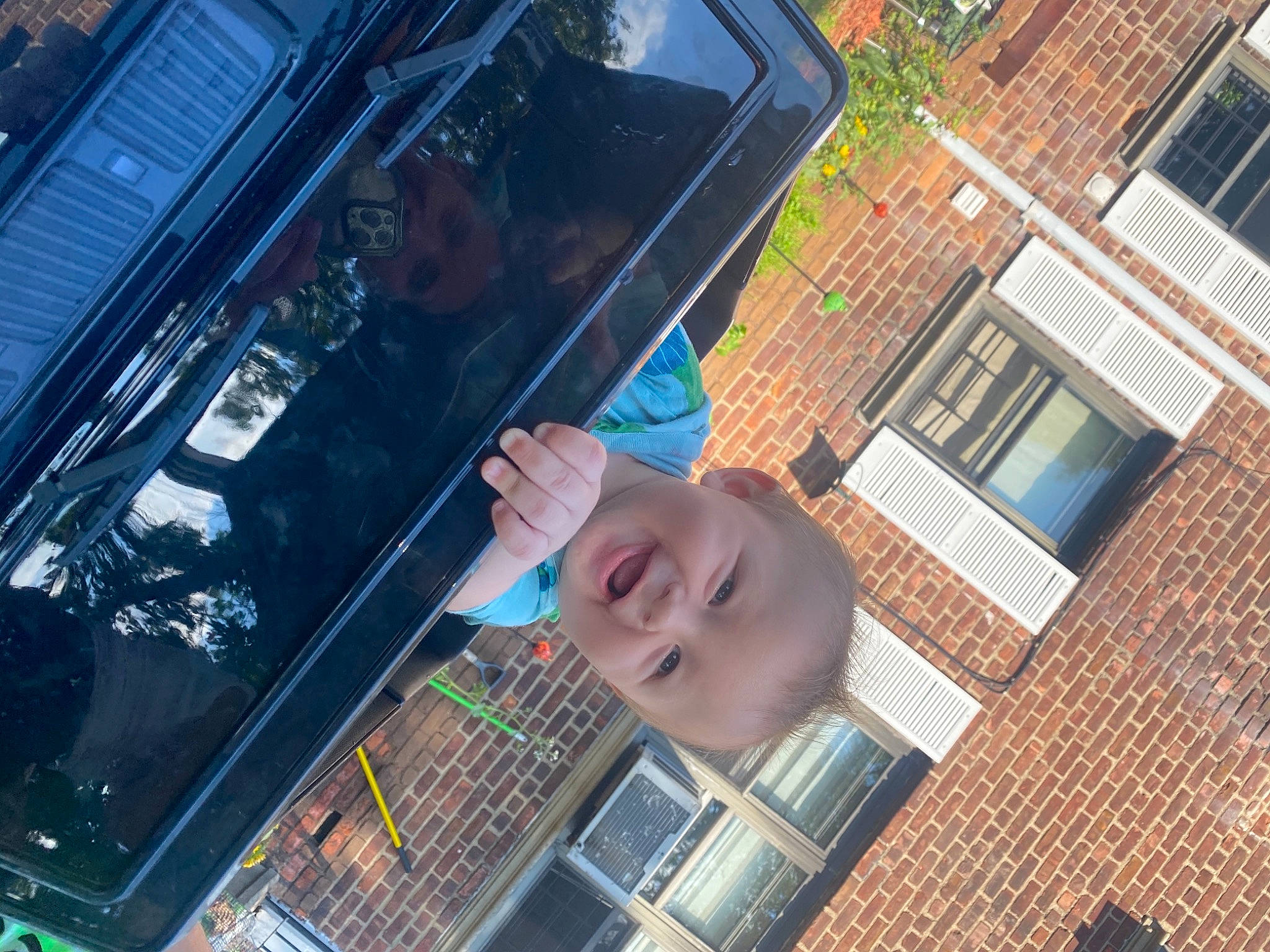 Maison is registered to the contest to win money with this photo: apartment, automotive_exterior, automotive_window_part, brick, brickwork, building, city, facade, fun, glass, house, leisure, machine, person, smile, t_shirt, toddler, vehicle_door, window, windshield