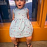 Gianna is registered to the contest to win money with this photo: child, girl, dress, pigtails, sandals, window, orange, heart_pattern, surprised_expression, blue_eyes, indoor, floor, cute, young_child, casual_clothing, person, portrait, sitting, fashion, happy
