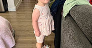 Gianna joined the competition — help win amazing prizes! toddler, child, indoor, smiling, standing, clothing, pile_of_clothes, couch, wooden_floor, pony_tail, sandals, pink_outfit, doorway, hallway, earrings, home, furniture, person, happy, floor