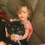 Boots joined the competition — help win amazing prizes! affection, animal, black_cat, blanket, casual_clothing, cat, child, couch, cozy, curly_hair, domestic, furniture, home, hugging, indoor, pet, portrait, seated, yellow_eyes, young_child