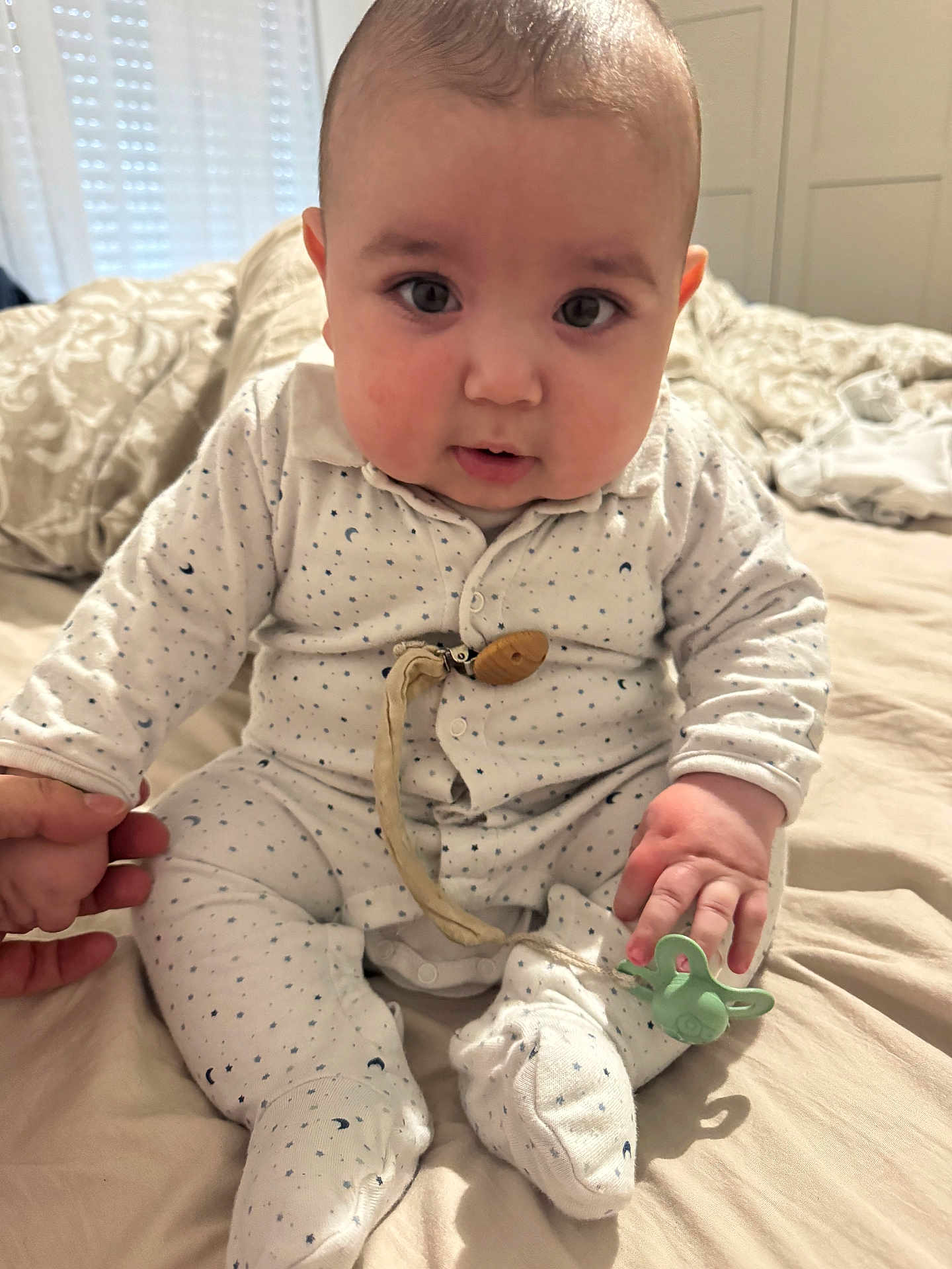 Asim participe au concours pour gagner de l'argent avec cette photo : baby, infant, onesie, pacifier, hand_holding, bed, bedroom, blanket, cute, chubby_cheeks, sitting, clothing, person, face, indoor, young_child, soft_lighting, sleepwear, expression, curious