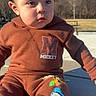 child, toddler, baby, portrait, outdoor, park, sitting, curious, face, eyes, brown_hair, sweatshirt, mickey_mouse, cartoon, clothing, playground, bench, trees, sunlight, advertisement