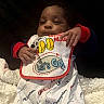 Je'Saiah is registered to the contest to win money with this photo: baby, infant, bib, clothing, champion, mickey_mouse, blanket, hand, face, person, cute, sleepy, indoor, soft_texture, colorful, red, white, blue, yellow, comfort