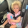 toddler, child, car_seat, stuffed_animal, toy, curly_hair, smile, pink, blue, pastel_colors, dress, footwear, car_interior, seatbelt, happy, sitting, young_child, safety, vehicle, cute