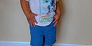Josiah joined the competition — help win amazing prizes! beige_wall, boy, casual_clothing, child, curious_expression, dinosaur_print, flooring, footwear, full_body, hands_on_hips, indoor, looking_away, portrait, short_hair, shorts, standing, tshirt, white_shoes, wooden_floor, young_child