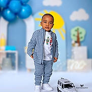 Josiah joined the competition — help win amazing prizes! toddler, child, blue_outfit, checkered_clothing, white_shoes, toy_car, balloons, sun, clouds, tree, indoor, portrait, fashion, cute, standing, playful_background, photography, smiling, young_child, casual