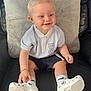 toddler, child, smiling, sitting, polo_shirt, shorts, white_shoes, socks, leather_chair, cushion, indoor, happy, blonde_hair, face, person, casual_clothing, footwear, young_child, home, comfort