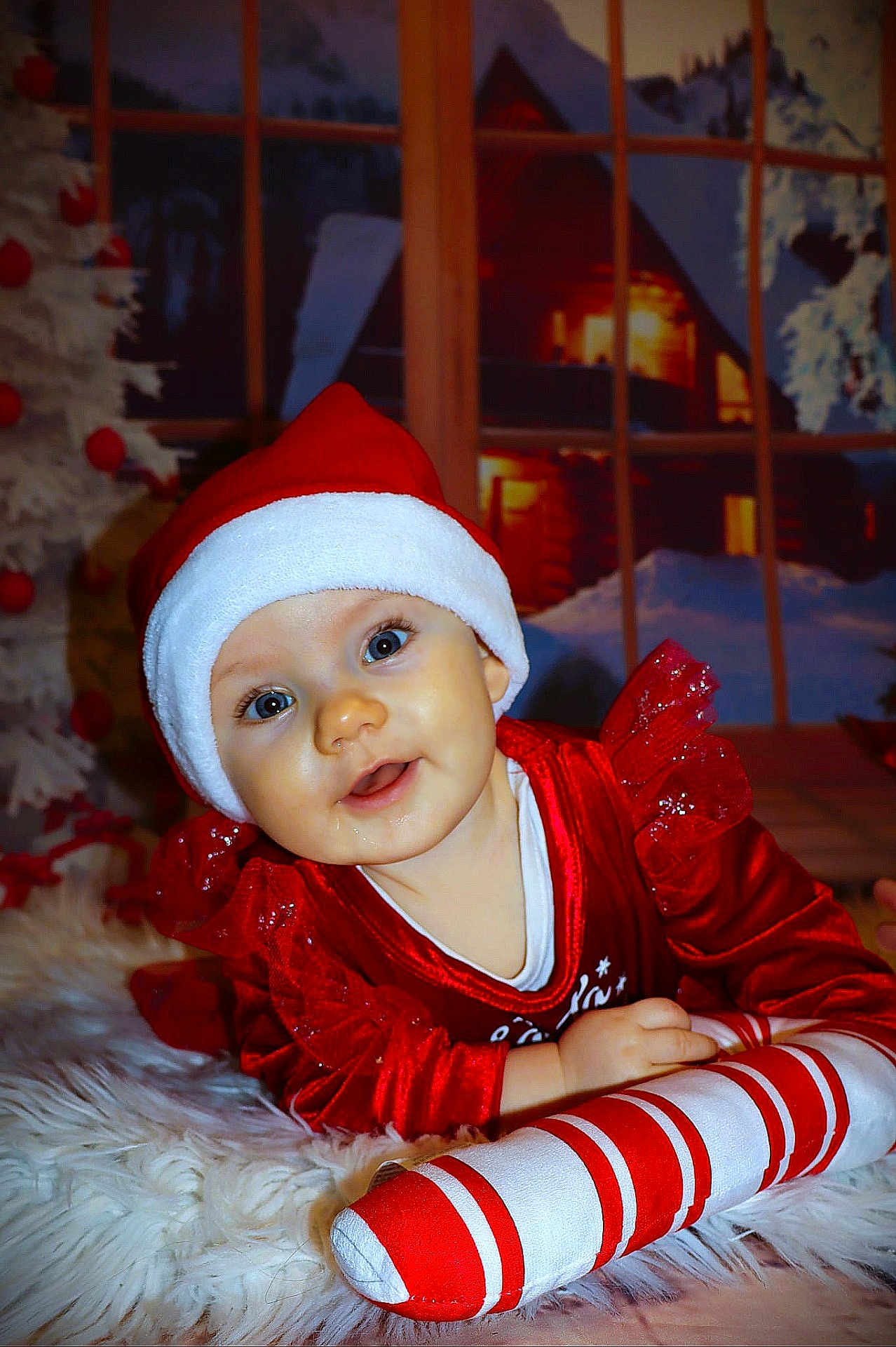 Agathe a rejoint le concours — aidez-le/la à gagner de superbes lots ! baby, child, santa_hat, red_clothing, plush_candy_cane, christmas, holiday, festive, smiling, face, blue_eyes, white_rug, indoor, window, winter_scene, decorations, happy, cute, portrait, holiday_spirit
