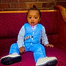 bench, blue_suit, brick_wall, casual_pose, child, confident, cute, fashion, formal_wear, furniture, indoors, maroon, person, portrait, sitting, striped_shirt, toddler, top_knot, white_shoes, young_child