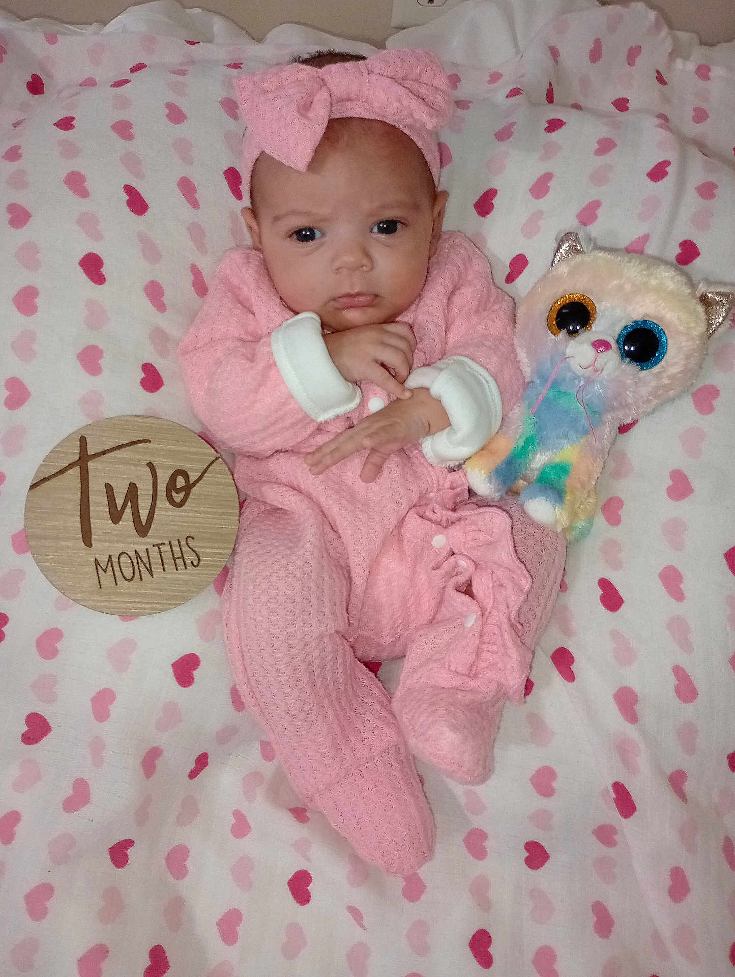 Amarah Love Saunders is registered to the contest to win money with this photo: baby, infant, pink_clothing, headband, plush_toy, heart_pattern, blanket, wooden_sign, milestone, cute, cozy, lying_down, newborn, two_months, soft_toy, portrait, indoors, child, smiling_face, baby_girl