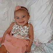 Amarah Love Saunders is registered to the contest to win money with this photo: baby, bed, blanket, child, clothing, comfort, cute, floral_top, girl, happy, headband, indoors, infant, pillow, pink_skirt, portrait, resting, sleepwear, smiling, young_child