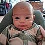 baby, child, clothing, cute, expression, eyes, face, furniture, head, human, indoor, infant, living_room, newborn, onesie, person, portrait, sitting, striped, television