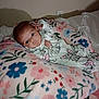 baby, infant, blanket, floral_pattern, onesie, cute, indoor, bed, sleepwear, child, person, resting, soft, cozy, portrait, newborn, face, sleeping_area, comfort, young