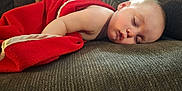 Levi joined the competition — help win amazing prizes! baby, sleeping, blanket, couch, child, face, peaceful, rest, indoor, soft_light, cozy, red_blanket, infant, relaxation, comfort, portrait, furniture, skin, young_child, home