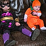 Athena joined the competition — help win amazing prizes! child, costume, pumpkin, superhero, mask, couch, leather, purple_tights, orange_outfit, baby, toddler, indoor, bookshelf, mushroom_decor, wood_floor, smiling, sitting, home, playful, cute