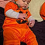Athena joined the competition — help win amazing prizes! baby, child, pumpkin_costume, orange, blanket, soft_toys, cute, infant, costume, headwear, hand, couch, clothing, indoor, portrait, lying_down, fabric, sleepwear, comfort, toddler