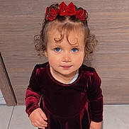 Gabriella a rejoint le concours — aidez-le/la à gagner de superbes lots ! child, toddler, girl, curly_hair, red_bow, blue_eyes, velvet_dress, burgundy, portrait, indoor, wood_background, tile_floor, standing, looking_up, hands, smile, cute, holiday_outfit, closeup, young_child