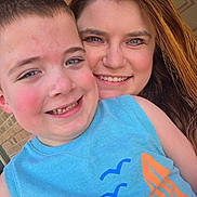 Colt is registered to the contest to win money with this photo: blue_shirt, brick_wall, casual, child, closeup, eyes, face, family, friendly, hair, happy, outdoor, person, portrait, rosy_cheeks, skin, smile, together, warmth, woman