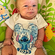 Gabriel participe au concours pour gagner de l'argent avec cette photo : baby, infant, onesie, stitch, 2025, playmat, giraffe, monkey, cartoon, cute, child, smiling, hand, legs, face, clothing, colorful, indoor, person, portrait
