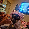 bed, bedroom, blanket, bonnet, brown_skin, child, cute, dog, door, furniture, hand, headband, home, indoor, pajamas, pet_clothing, playful, smiling, television, wall_decor