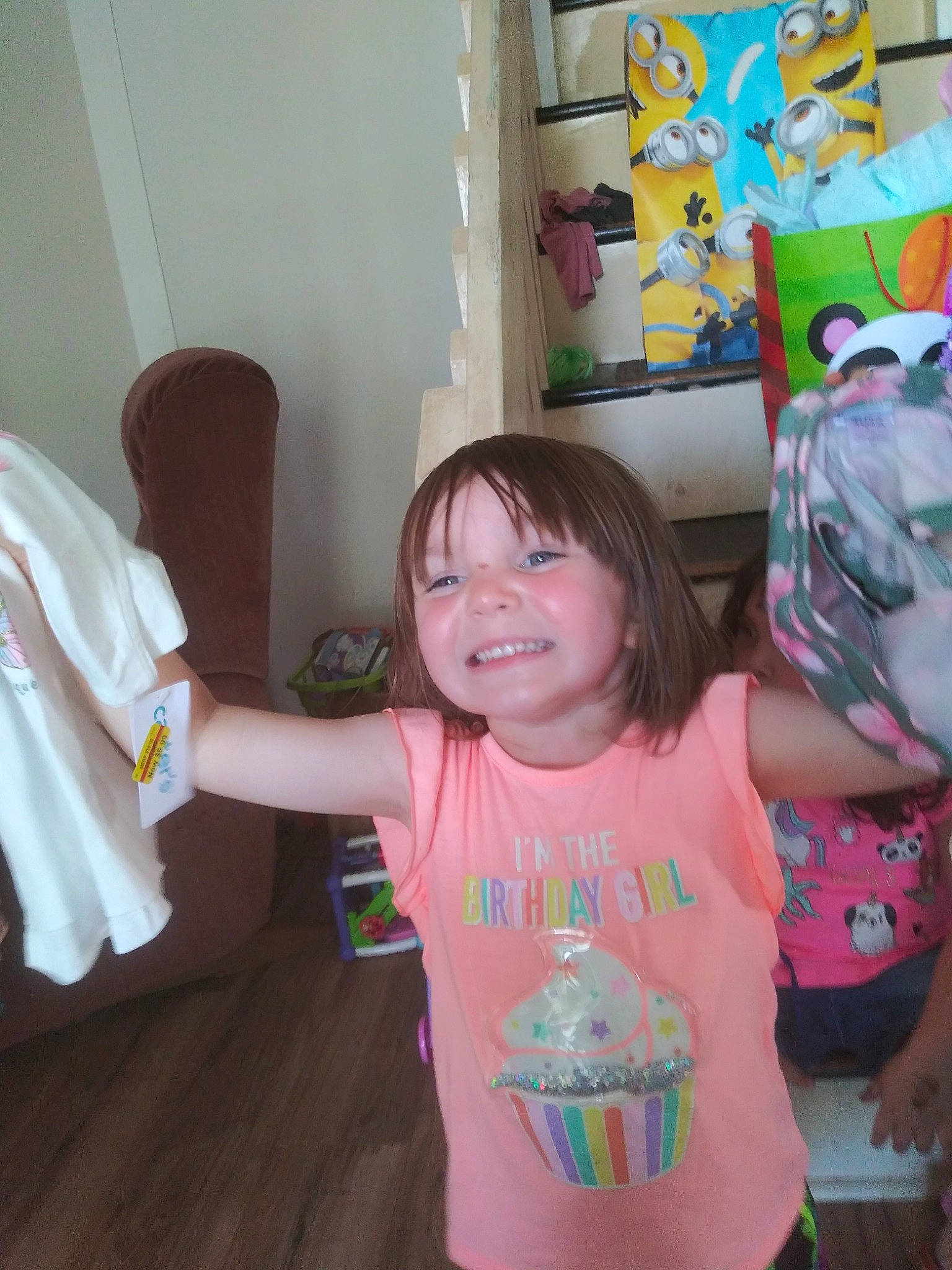 Annabel is registered to the contest to win money with this photo: arm, baby_toddler_clothing, child, curtain, finger, fun, gesture, happy, joy, leisure, mouth, person, pink, play, room, sleeve, smile, standing, t_shirt, thumb