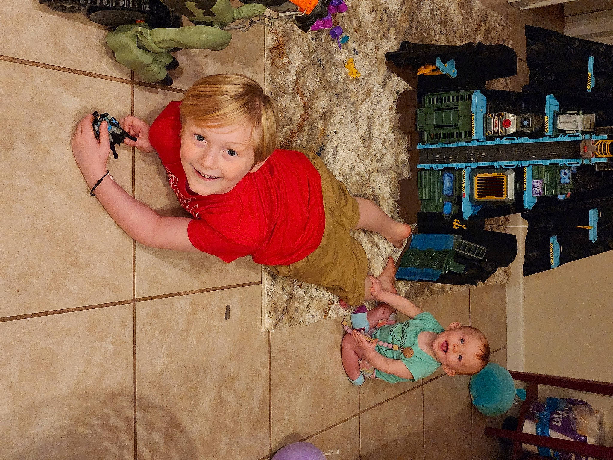 Zander is registered to the contest to win money with this photo: child, flooring, fun, happy, joy, leisure, person, pink, play, room, shelf, shelving, sitting, t_shirt, toddler, toy, tree, vacation, visual_arts, wood