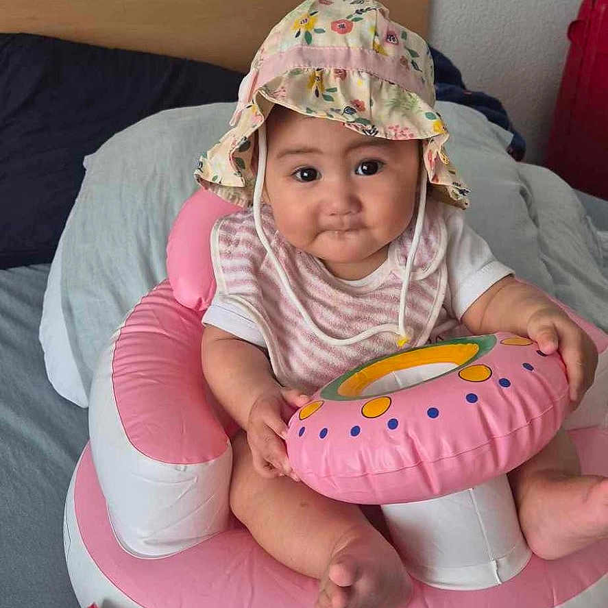 Mataura participe au concours pour gagner de l'argent avec cette photo : baby, bed, child, clothing, colorful, comfort, cute, face, hat, indoor, infant, inflatable, person, pillow, pink, play, sitting, smile, toy, young