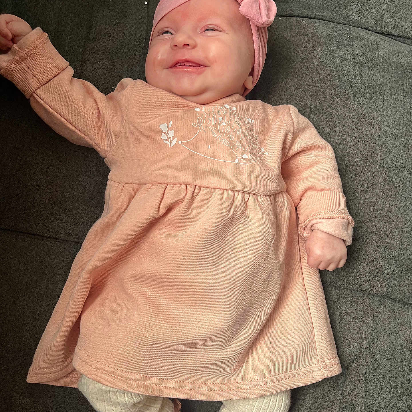 Nelya participe au concours pour gagner de l'argent avec cette photo : baby, child, clothing, couch, cozy, cute, footwear, happy, headband, indoors, infant, legwear, lying_down, person, pink_dress, portrait, relaxed, small_shoes, smiling, soft_fabric