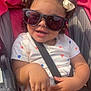 Luna is registered to the contest to win money with this photo: toddler, child, sunglasses, stroller, pink, curly_hair, bows, smile, white_dress, toy_car, sunlight, seatbelt, outdoor, cute, happy, baby, person, hands, legs, fashion