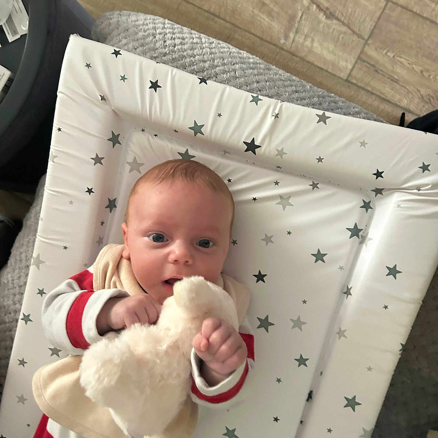 Nikolas joined the competition — help win amazing prizes! baby, blanket, changing_pad, child, cute, face, floor, hand, indoors, infant, pajamas, person, red_stripes, sleepwear, soft_toy, stars, stuffed_animal, toy, white, wood_floor