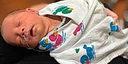 Easton is registered to the contest to win money with this photo: newborn, baby, sleeping, blanket, duck_pattern, nasal_tube, infant, wrapped, peaceful, closeup, person, child, bedroom, soft_focus, human, cute, healthcare, resting, swaddled, treatment