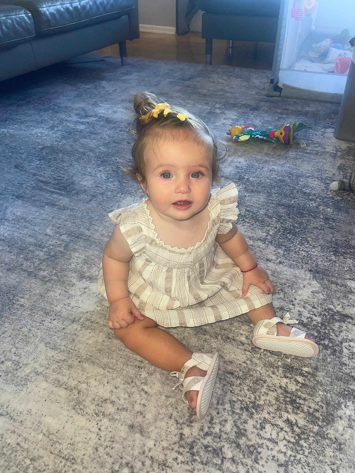 Michelle is registered to the contest to win money with this photo: toddler, child, baby, carpet, living_room, toy, shoes, dress, hair_bow, blue_eyes, sitting, floor, indoor, furniture, curious, cute, small, home, person, childhood