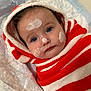 baby, child, face, blue_eyes, cream, towel, striped, red, white, hood, skin_care, cute, infant, wrapped, portrait, lying_down, soft_surface, close_up, indoors, expression
