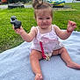 baby, child, outdoor, grass, blanket, toy, penguin, summer, nature, water, greenery, cute, playful, person, infant, pacifier_clip, top_knot, expression, sitting, happy