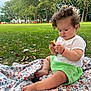 Michelle is registered to the contest to win money with this photo: toddler, child, baby, grass, blanket, food, park, outdoor, greenery, trees, curly_hair, shorts, white_shirt, barefoot, summer, nature, daylight, leaves, sitting, cute