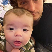 Jackson joined the competition — help win amazing prizes! baby, adult, face, closeup, indoor, portrait, person, curious, expression, camo_clothing, hair, skin, eyes, mouth, casual, toddler, head, shoulder, blanket, cozy