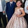 child, boy, girl, formal_wear, suit, dress, party, event, posing, smile, indoor, carpet, people, adult, fashion, celebration, hair, face, hand_on_hip, confident