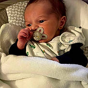 Ilenzo a rejoint le concours — aidez-le/la à gagner de superbes lots ! newborn, baby, pacifier, blanket, infant, cute, sleeping_bag, soft, clothing, face, hand, indoors, child, portrait, resting, cozy, pattern, head, babywear, comfort