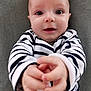 baby, infant, child, face, hands, striped_clothing, black_and_white, smile, expression, curious, closeup, portrait, cute, soft_background, indoor, person, skin, head, eyes, young